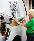 Woman applying clear adhesive vinyl to a van, illustrating Clear Contact Paper 17.7 Inch Wide 118 Inch Long Peel And Stick Self Adhesive Vinyl For Cricut Transfers Transparent Book Covers Removable Wallpaper Roll DIY Friendly Waterproof Surface Protector.