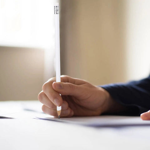 Close-up of hand writing with 10 Pack White Shaft Carpenter Marking Pencils With Eraser Non Sharpened Round Lead Graphite Pencils.