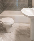 Clean modern bathroom with gray tiled walls, white toilet, bathtub, and sink, ideal for using Antibacterial Disinfectant Cleaner Lemon Scent.