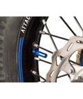 Tusk blue rim lock nut spacer kit installed on motorcycle wheel with disc brake rotor.