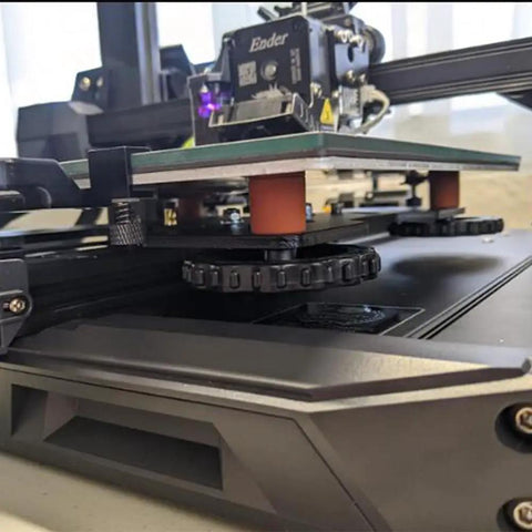 Silicone Bed Mounts And Spacers Kit for 3D printers under Ender 3, showing orange silicone mounts and tightened bed leveling parts.