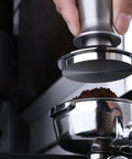 Top-Tier Coffee Tamping Station With Built-In Espresso Knock Box And Portafilter Holder Keeps Your Bar Setup Crisp Fits 58mm Portafilters, showing a hand using a metal tamper on coffee grounds in a portafilter.