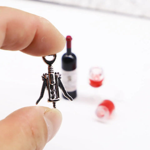Hella Cool Miniature Red Wine Bottle Set Featuring Two Resin Filled Wine Glasses And A Static Corkscrew displayed in hand.