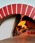 Pizza cooking in a red-brick wood-fired oven with visible flames inside