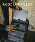 Person placing a laptop into padded sleeve of Prvke Zip 21L V4 Photography Bundle Weatherproof Travel Camera Backpack on table.