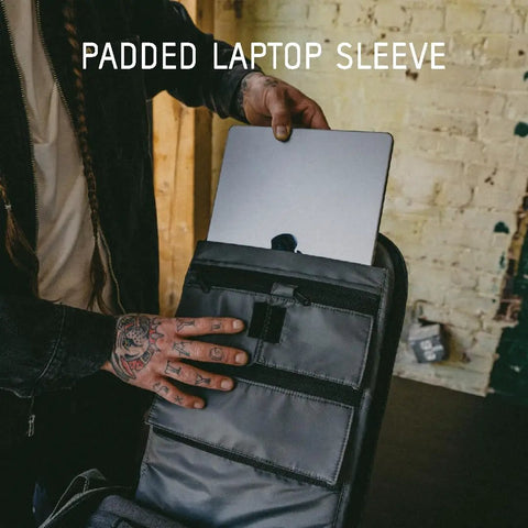 Person placing a laptop into padded sleeve of Prvke Zip 21L V4 Photography Bundle Weatherproof Travel Camera Backpack on table.