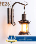 2 In 1 Black Rustic Wall Light With Industrial Glass Shade Lantern Metal Wall Sconce glowing on white wall