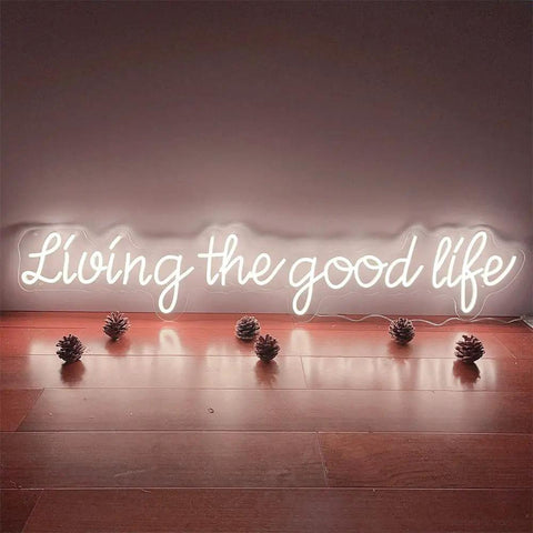 Living The Good Life LED Neon Sign Custom Personalized Home Wall Decor Large 30 Inch Indoor Light warm white glow on wood floor.