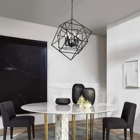 Cubist Pendant Metron Chandelier in black with interlocking open cube frame hangs above a white dining table with black chairs.