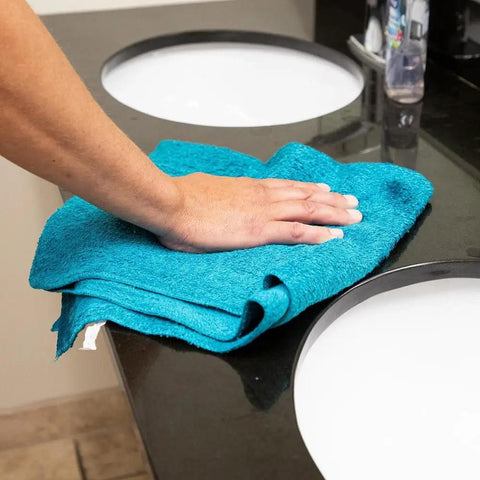 Hand cleaning a countertop with Blue Virgin Huck Cotton Rags 25 Inch By 16 Inch Lint Free Cleaning Cloths, 50 Pound Box, 5 To 7 Pieces Per Pound, Workhorse Wipe Down Rags For Auto Shop And Home Use.