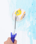 Double Ended Paint Roller Corner Tool With Comfy Grip Handle For Easy Wall Painting, handheld on a painted wall.