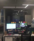 Office with dual monitors, one displaying a panda, with sleek integrated LED tube lighting in ceiling setup.