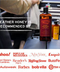Two Leather Honey leather conditioner bottles in a car interior; amber glass with black caps, front 8 oz bottle