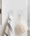 Sick Wall Mount Hooks, Totally Rust Proof Storage Rack For Coats, Bags, And Picture Hanging, white towel and loofah hanging on clear hooks.