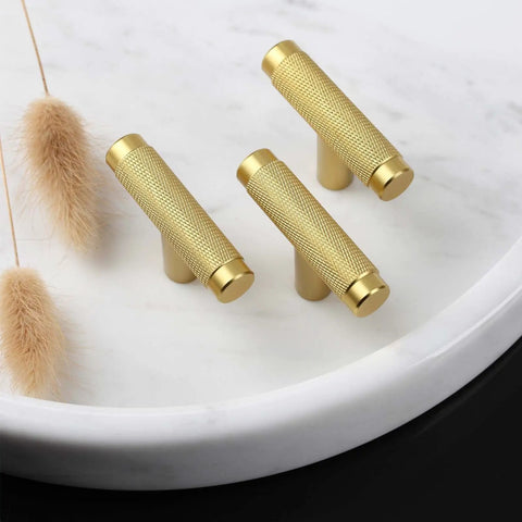 Brass cabinet pulls with knurled texture on marble tray