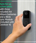 Hella Durable Wireless Security Camera Bundle With Video Doorbell Offering Two Year Battery Life For Zero Stress Setup And Badass Night Vision Coverage. A hand mounting the video doorbell on a textured wall.