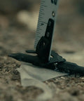 Kickin Tough 35 Foot Tape Measure Featuring Double Sided Blades And Grippy Magnetic Hook Military Hardened Composite Shell on dirt.