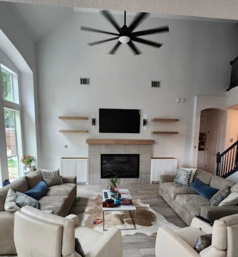 Living room featuring sofas, a coffee table on a rug, and a large TV above a fireplace in a relaxed interior design.