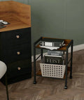 Two Tier Rolling Utility Cart with Brown Wood Shelves and Black Metal Frame on Wheels next to a desk in an office setting.