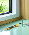 Pocket Sized Fencing Sword Tip Screwdriver With Anti Slip Handle next to a metal piece on a green surface by a window