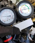 Automotive cylinder leak-down tester kit with dual gauges and extension rod, front view on engine.
