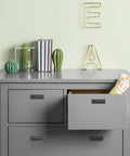 Gray dresser with open drawer, books, and decorative items