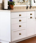 Antique Brass Cabinet Knobs 6 Pack With Spacers And Backplates mounted on white kitchen cabinets, vintage style hardware
