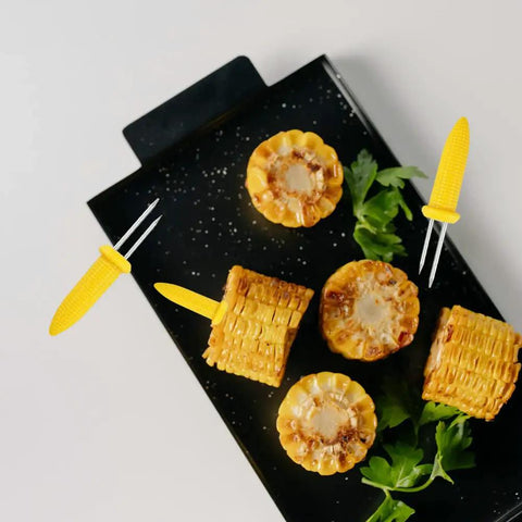 24 Pack Stainless Steel Corn Holders For Grillin And Barbecue Cob Skewers with corn slices on a black tray, 2.36 inch length.