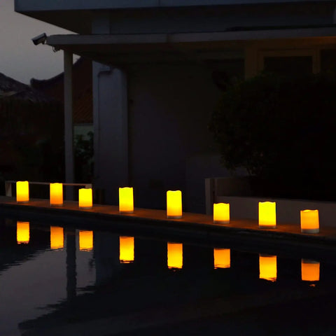 Lit Outdoor Solar Pillar Candles 3x6 Inches Waterproof Rechargeable Flameless Flickering Lights With Dusk To Dawn Sensor along a pool edge
