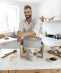 Man using Rock Solid Manual Granite Stone Grain Mill With Wooden Base And Hand Crank Heavy Duty Grinder For Home Use in kitchen