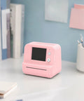 Totally Rad Pink Mini Thermal Printer With AI Voice Recognition And Built In Display on a desk with books and stationery.
