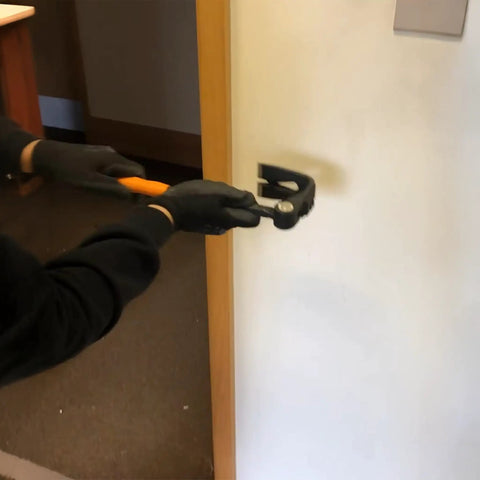 Using Heavy Duty Indexing Crowbar And Nail Puller Wrecker Tool for removing trim with gloves on a wall.