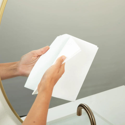Spiff cleaning cloth, white, held by hands near bathroom sink and mirror