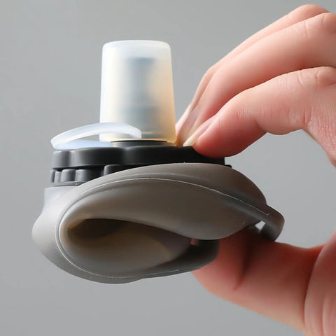Close-up of a gray Hands Free Hydration Wrist Bottle for Runners, 200ml, silicone, leak-proof, ergonomic grip for workouts.