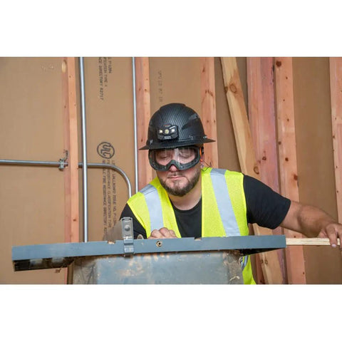 Construction worker wearing clear lens safety goggles with anti fog, scratch-resistant eye protection PPE on job site.