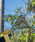 Gloved hand using Chicago Grip For Bare Wire With Three Inch Jaw, V Groove Cable Clamp in field setting.