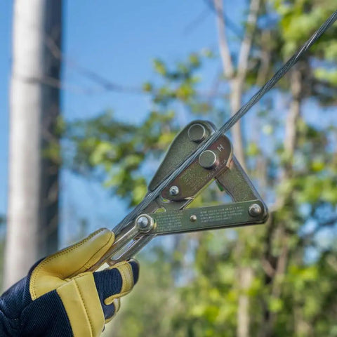 Gloved hand using Chicago Grip For Bare Wire With Three Inch Jaw, V Groove Cable Clamp in field setting.