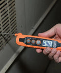 Person using IR07 Dual Infrared And Probe Pocket Size LCD Digital Thermometer near a vent, displaying 69.0F.