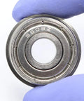 Four Pack Heavy Duty SF608ZZ Flanged Ball Bearings Stainless Steel Double Shielded Motor And Fan Parts Smooth Rotary Motion For Wheels, close-up of bearing with a gloved hand.