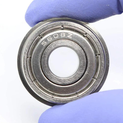 Four Pack Heavy Duty SF608ZZ Flanged Ball Bearings Stainless Steel Double Shielded Motor And Fan Parts Smooth Rotary Motion For Wheels, close-up of bearing with a gloved hand.