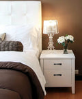 White bedside table with Arch Cabinet Pulls 3 Inch Matte Black Solid Zinc Die Cast flat drawer handles, lamp, and flowers