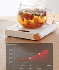 Electric Coffee Mug Warmer For Office Desk With Auto Shut Off Timer Keep Your Brew Piping Hot Straight Up Skip The Microwave Hassle flat bottom cup heater with tea on tabletop.