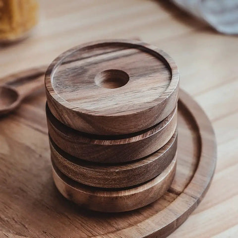 Top Shelf Airtight Glass Storage Jars With Smooth Acacia Wood Lids Keeps Your Daily Drip Locked Up Tight For Coffee Beans Tea And Dry Goods In This Bpa Free Four Pack Kitchen Essential with stacked wooden lids on a table.