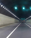 Heavy Duty Led Flood Light For Outdoor Security And Garage Spots illuminating a tunnel with reflective walls and green traffic lights.