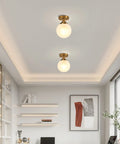 Milk Glass Globe Semi Flush Mount Ceiling Light With Gold Brass Finish Mid Century Modern Style in elegant interior space.