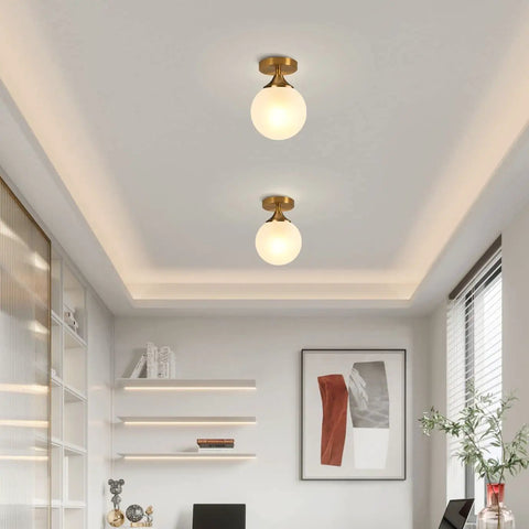 Milk Glass Globe Semi Flush Mount Ceiling Light With Gold Brass Finish Mid Century Modern Style in elegant interior space.