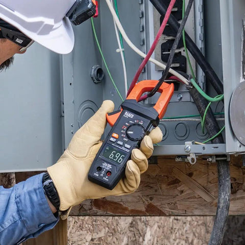 Electrician using Digital Clamp Meter With True RMS And LoZ Auto Ranging For AC And DC Voltage And Current Continuity Frequency Capacitance NCVT Temperature Diode Test 1000V Rating Built In Flashlight Rugged Pro Grade Tool on electrical panel