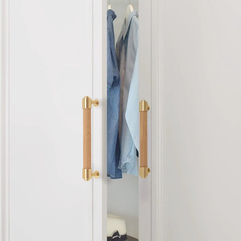 Modern Mid Century brass and wood cabinet pulls on white closet door