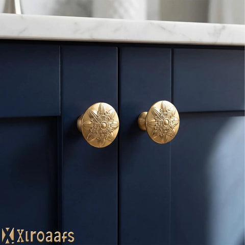 Close-up of champagne bronze floral cabinet knobs installed on blue kitchen cabinets, highlighting vintage round design.
