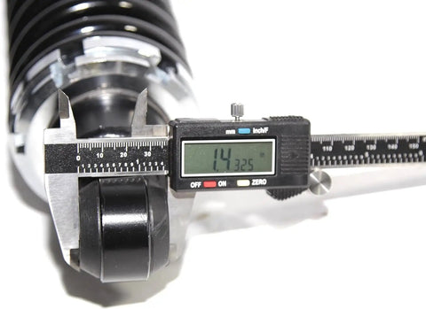 Close-up of digital caliper measuring rear left and right street rod coil over shocks with black coated springs 400 pound rate.